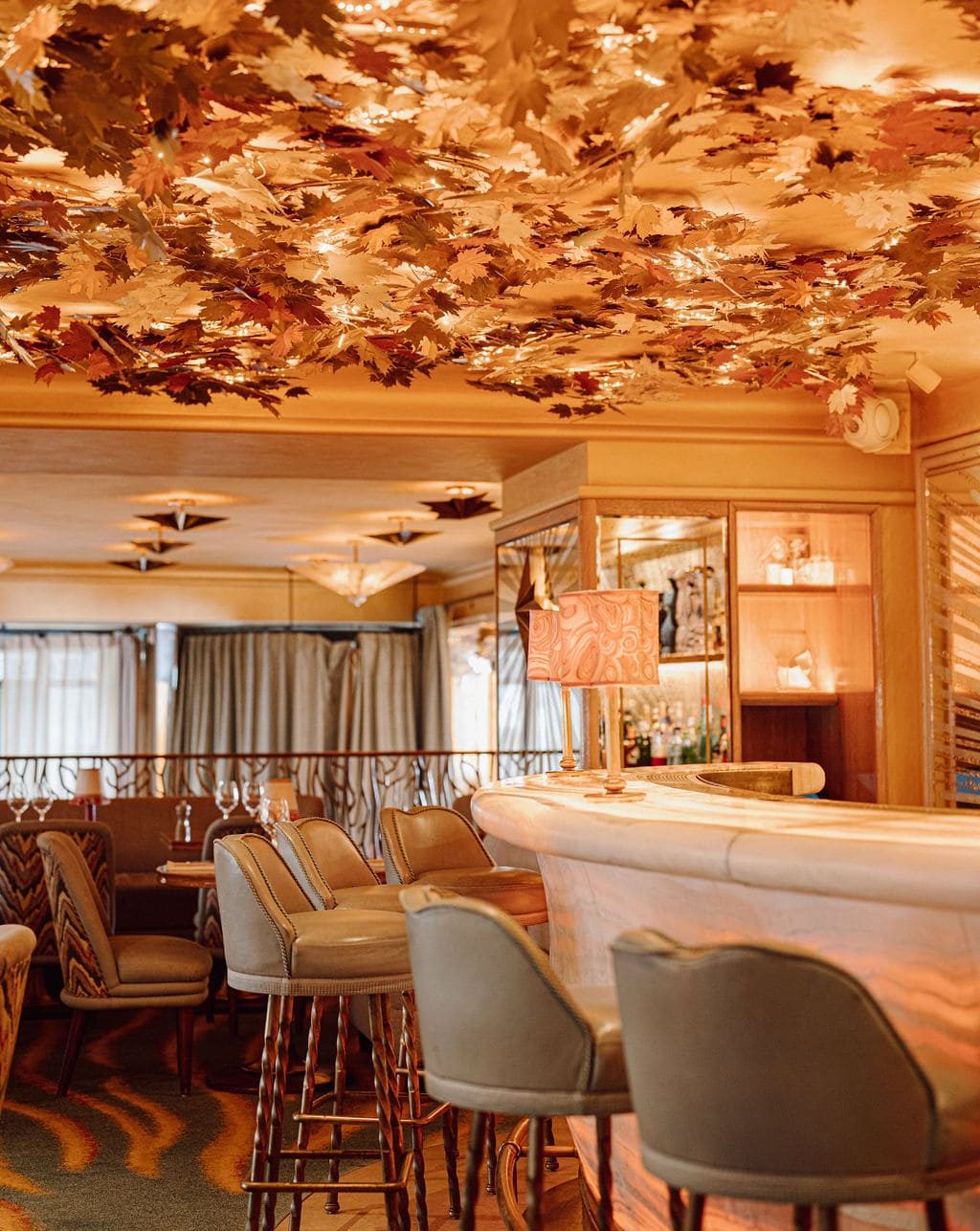 Elegant bar at Les Jardins du Presbourg in Paris with a golden leaves decorated ceiling and warm ambiance.